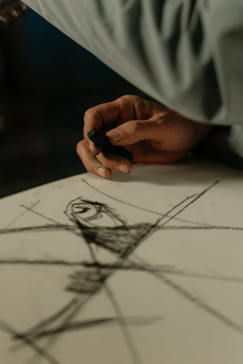 A detailed view of a hand sketching an abstract drawing on paper, emphasizing creativity and artistry.
